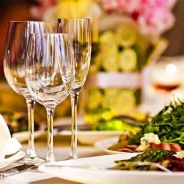 A plate with tossed green salad next to wine glasses.